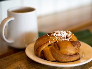 Närbild på kanelbulle och kaffekopp.