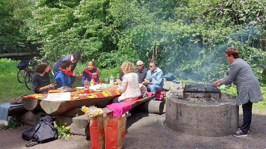 Personer sitgter vid en grillplats och samtalar.