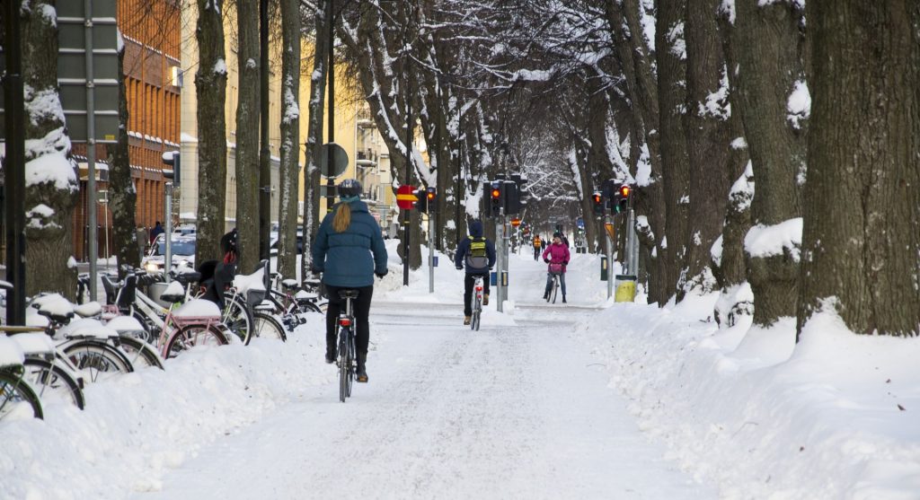 Bilen är tagen bakifrån på en kvinna som cyklar i ett vinterlandskap.