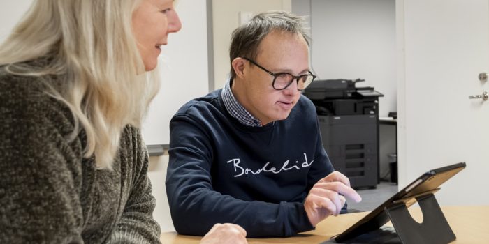 Två personer som sitter vid ett bord med en surfplatta