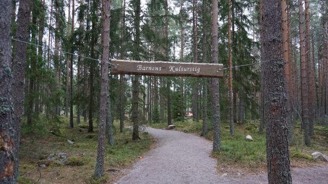 Skylt i trä med texten "Barnens kulturstig". I bakgrunden syns skog.