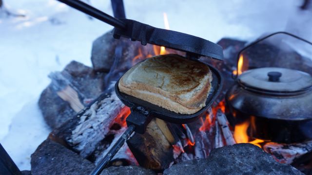 Smörgås som grillas över öppen eld.