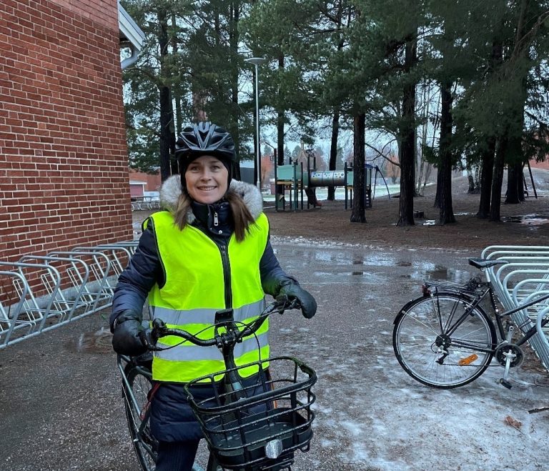 En kvinna med reflexväst och hjälm på cykel