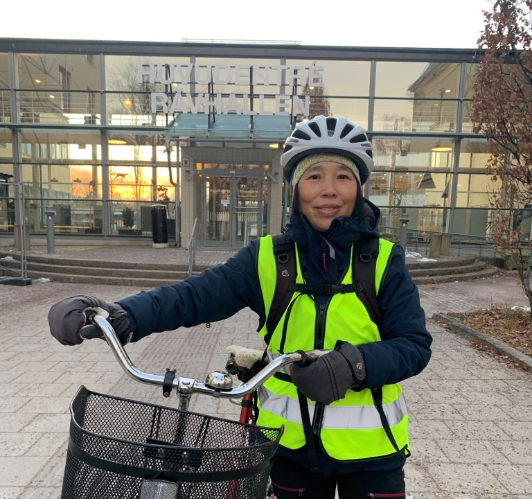 En kvinna med reflexväst och hjälm på cykel