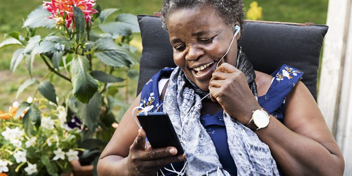 Kvinna från Tanzania pratar i telefon i trädgård.