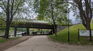 Gång- och cykelvägen som går under Kvarnbron. Lövträd och Gavleån syns i bakgrunden. Flera människor vandrar i området.