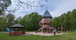 Stadsträdgårdens lekplatsområde och den stora rutschkanan. Två barn leker. I bakgrunden visas flera gröna träd. 