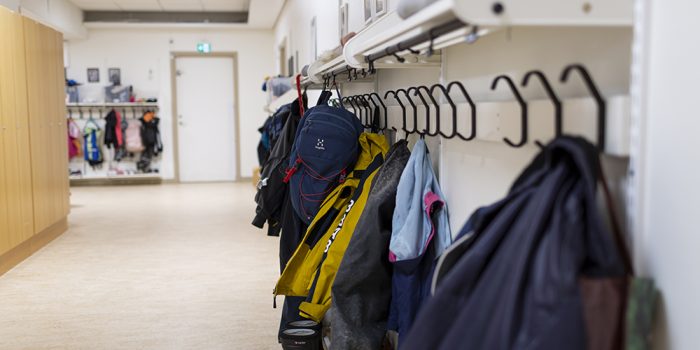 Ytterkläder hänger på rad i en skolkorridor.