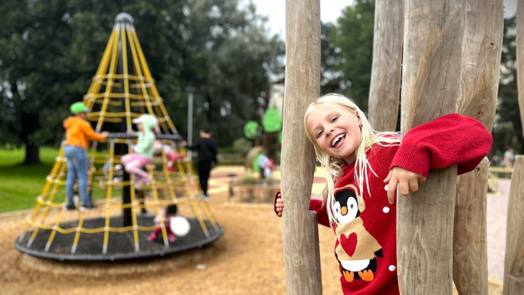 Barn leker i Sätraängarnas lekplats. På bilden syns en gul konformad klätterställning och trädställningar