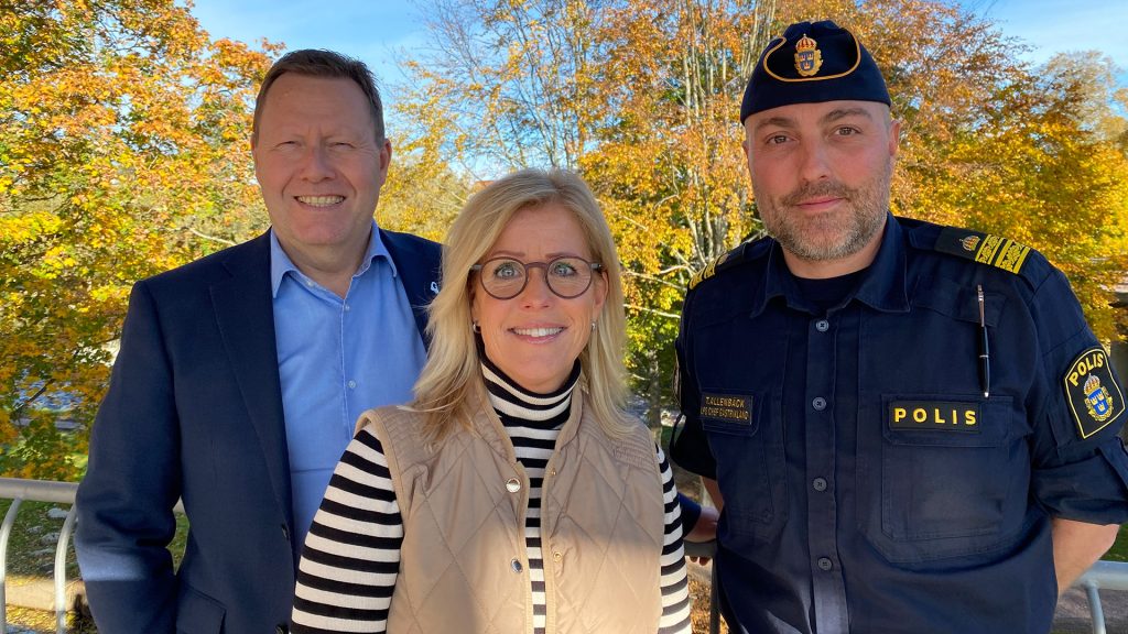 Tre personer står tillsammans. En man, en kvinna och en polis