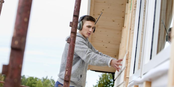 Ung person bygger på ett hus.