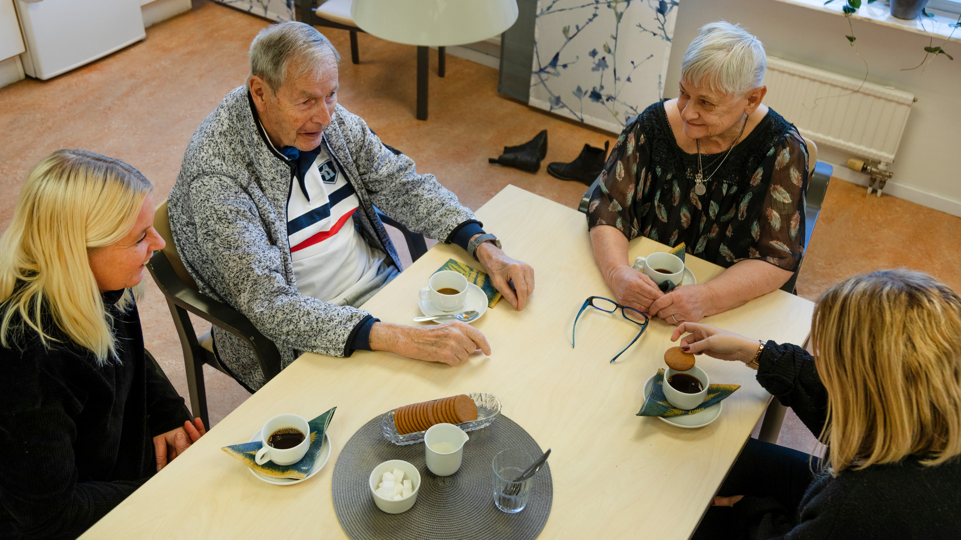 Äldre dam och herre sitter och fikar tillsammans med personal.