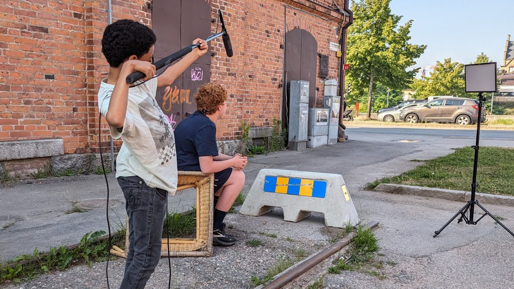 Barn håller i en bomarm med mikrofon under en filminspelning