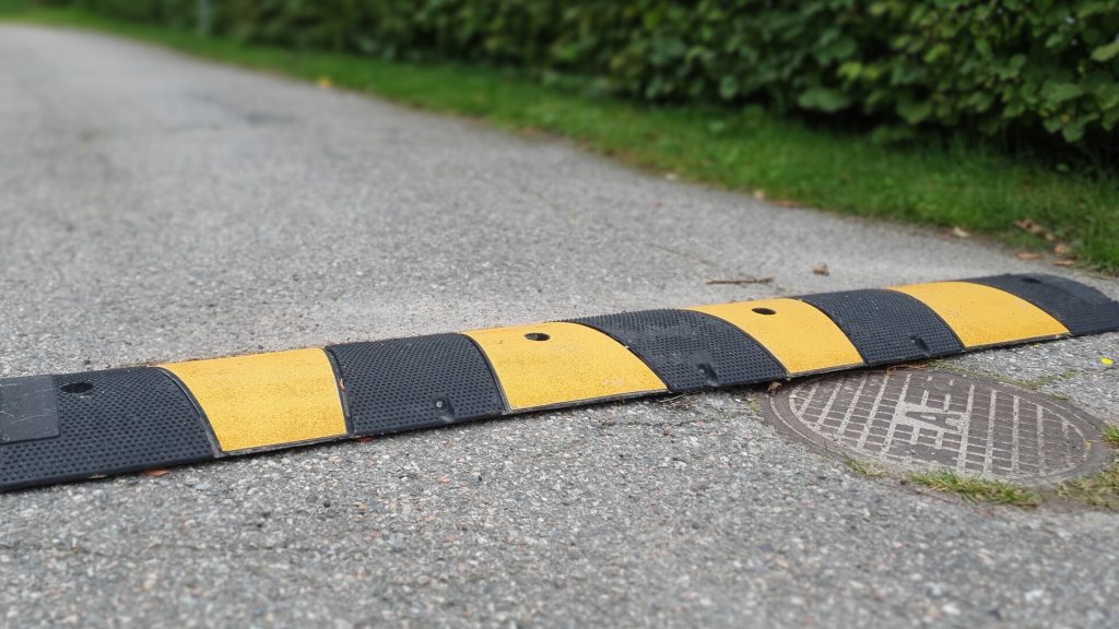 Bilden visar ett liggande fartgupp på en asfalterad gata
