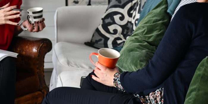 Två personer sitter i en soffa med en varsin kaffekopp i handen