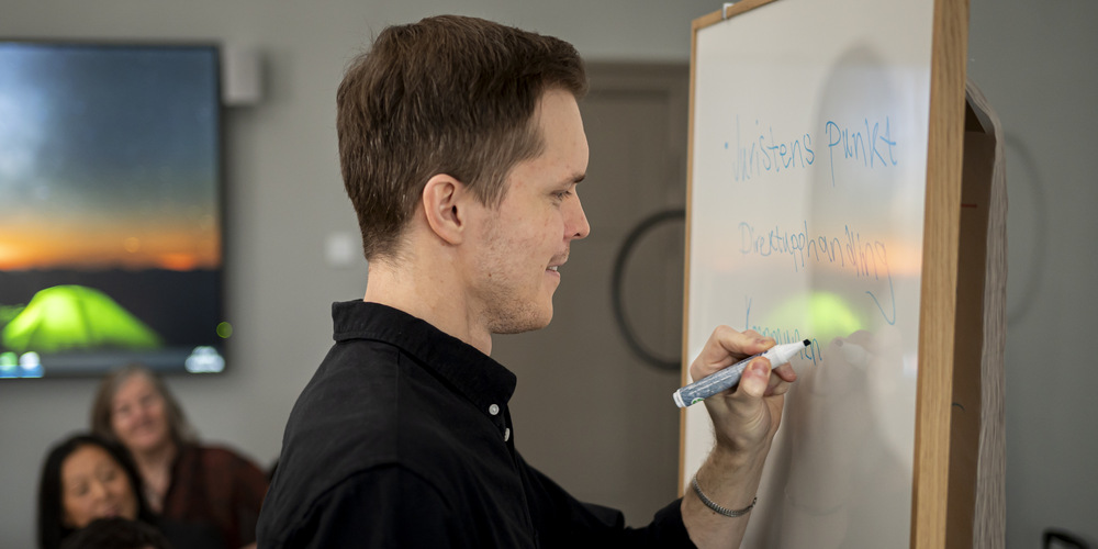 Person skriver på White board.