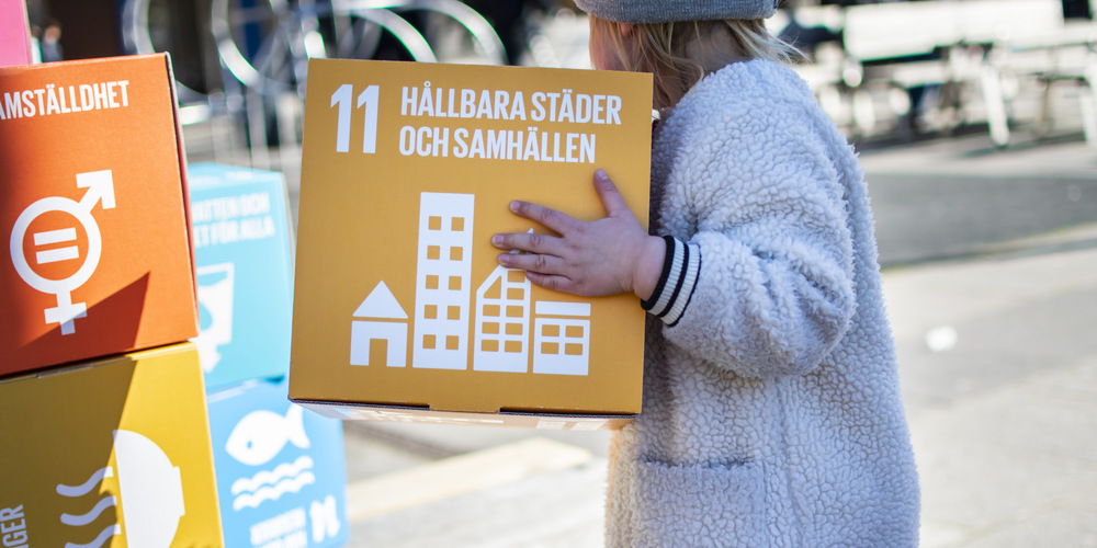 Ett barn som håller i en pappersbox med ett av budskapen från de globala målen
