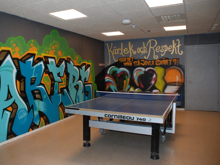 Ett rum med graffiti på väggarna och ett pingisbord i mitten.