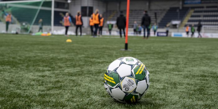 En fotboll i förgrunden under en fotbollsträning