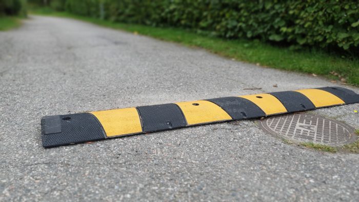Ett gult och svart fartgupp som ligger på en asfalterad väg.