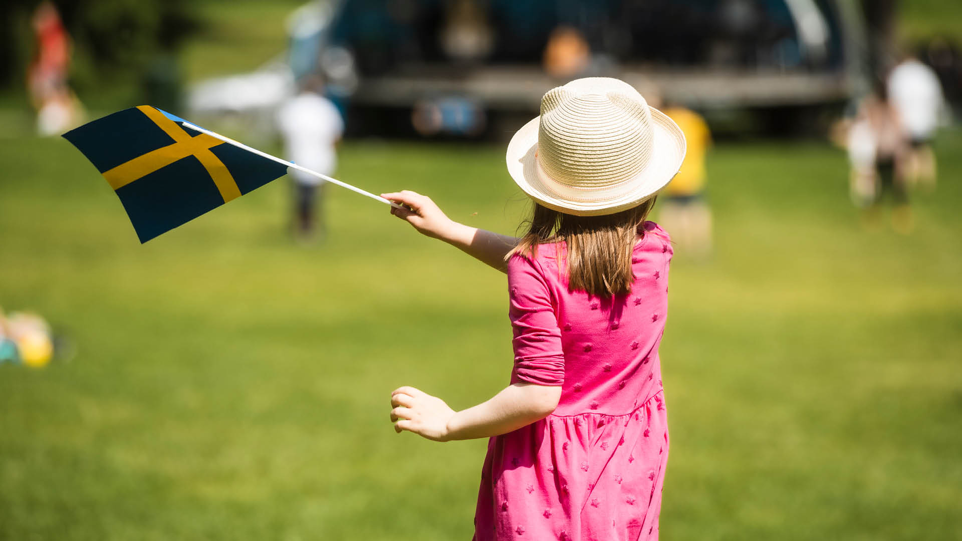 En bild på ett barn med svenska flaggan i handen