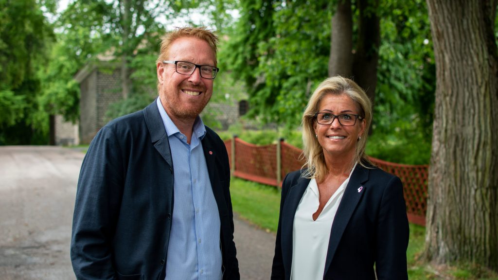Två personer ler mot kamera utomhus i grönområde.