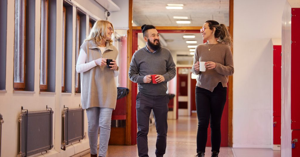 Tre personer i skolkorridor. Troligen lärare.