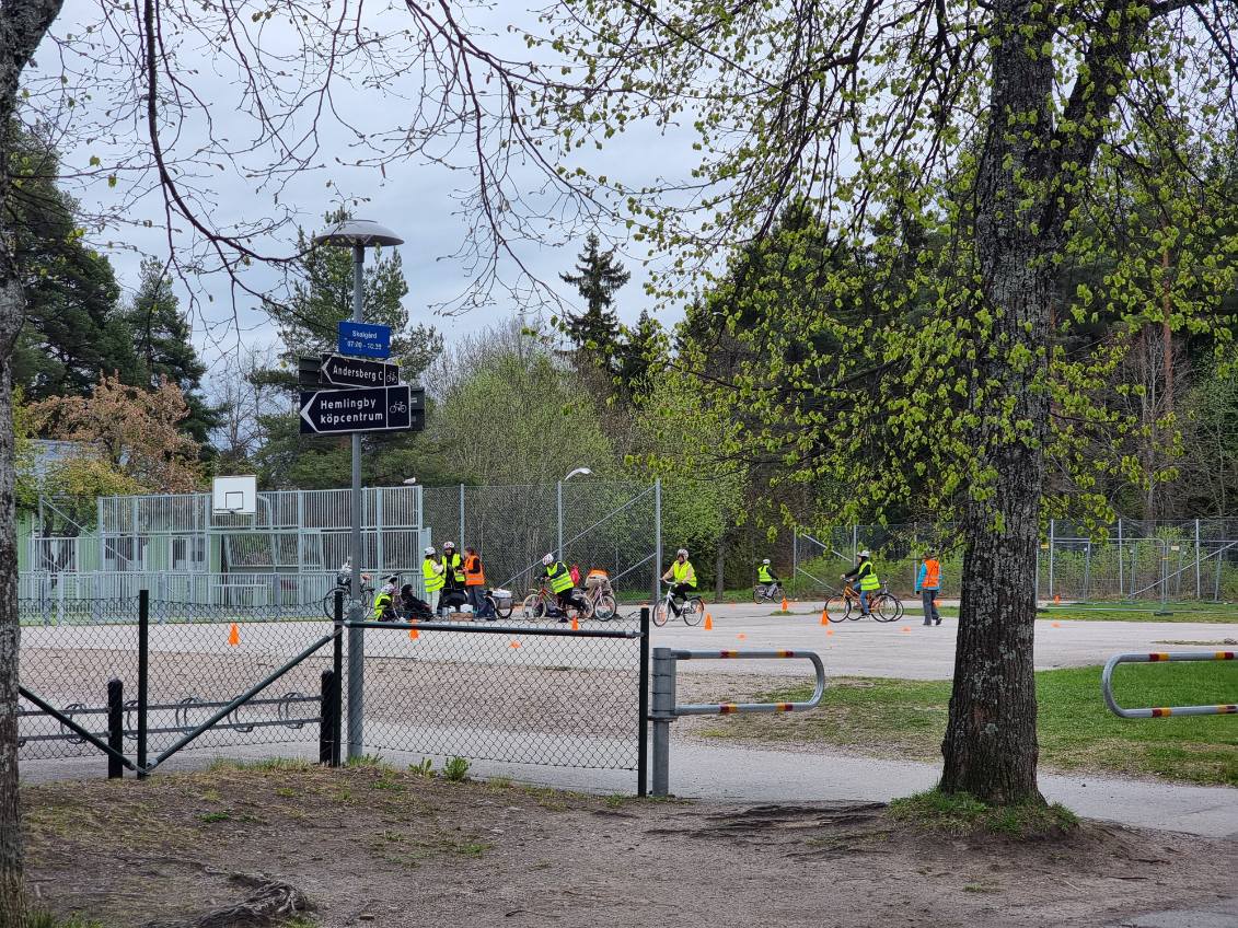 En grupp vuxna i gula västar som cyklar på asfaltplan.