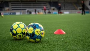 Två fotbollar på en plan.