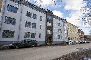 Bilar parkerade på en gata utanför ett lägenhetshus.