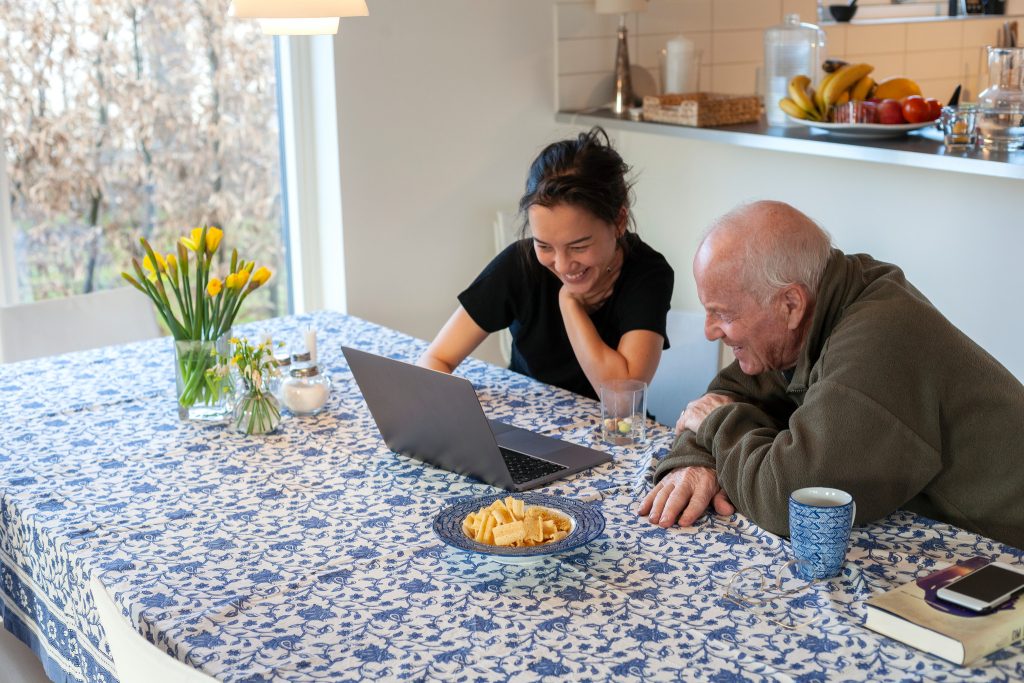 Två personer som sitter vid ett köksbord med en bärbar dator