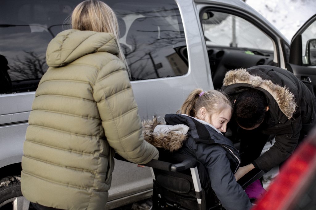 Assistenter hjälper ung kvinna som är rullstolsburen