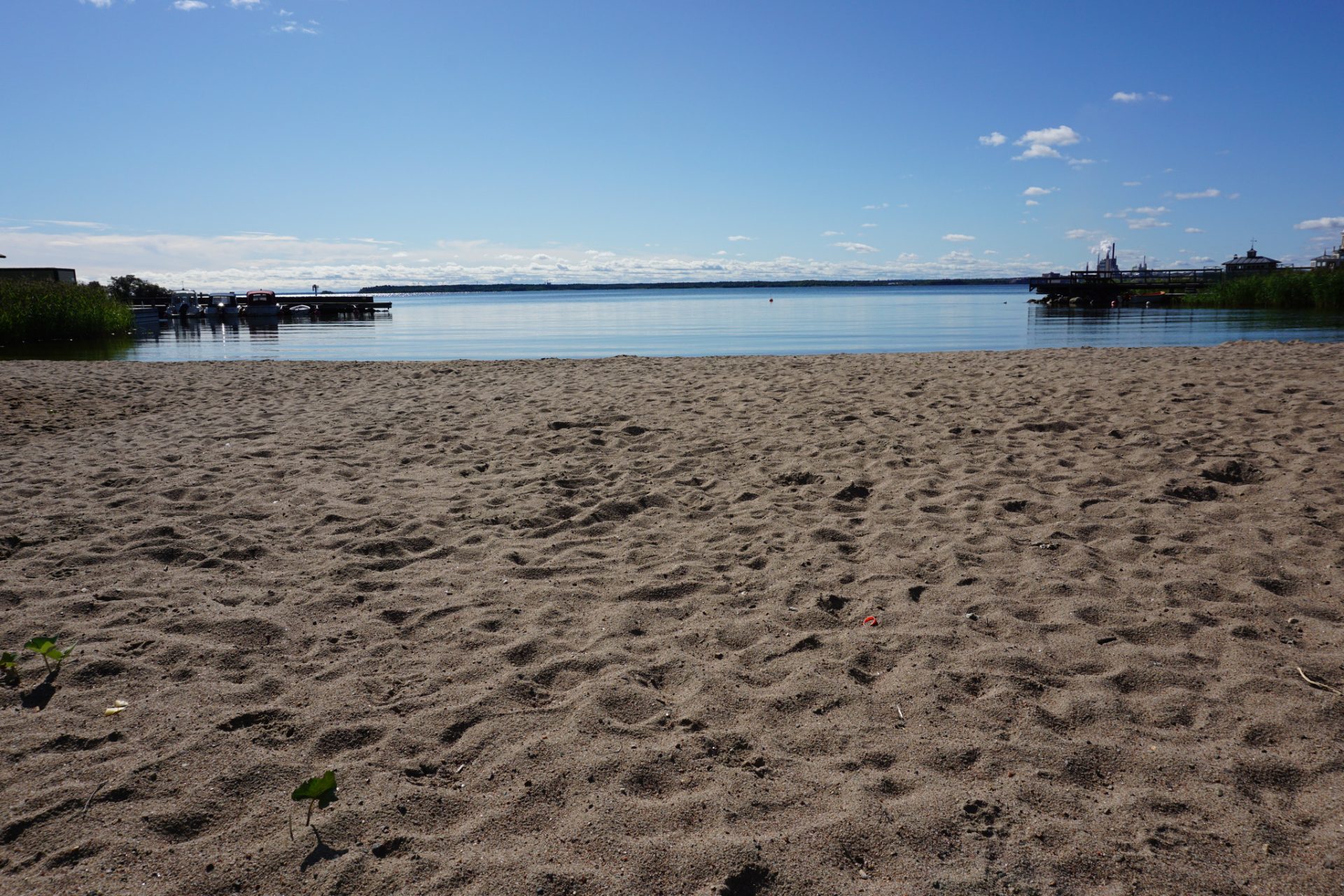 Sandstrand och vatten med bryggor.
