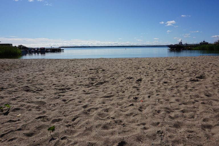 Sandstrand och vatten med bryggor.