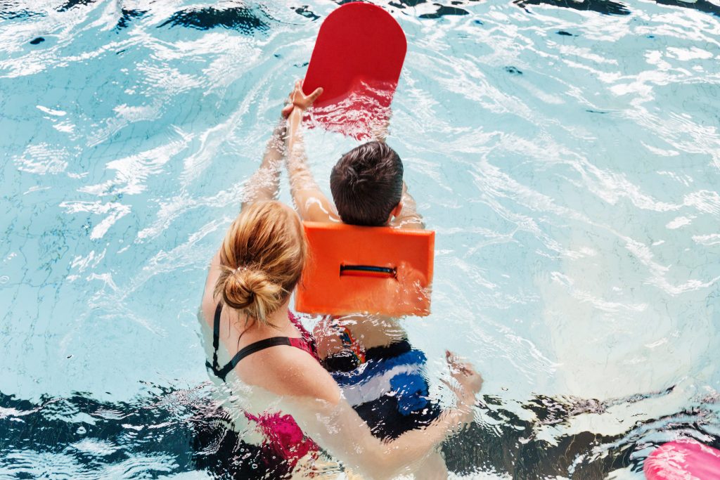 vuxen och barn i en pool som tränar på att simma