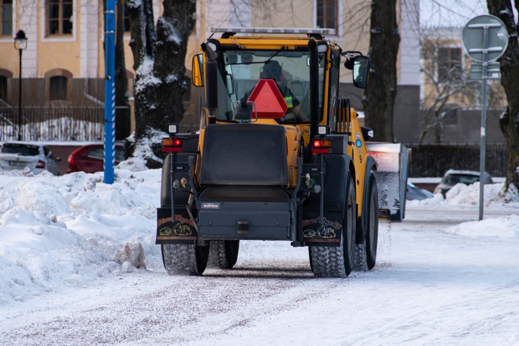 Traktor som sprider ut sand på en väg