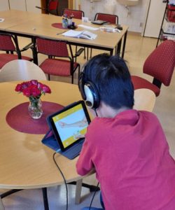 En person med hörlurar arbetar med Sfi på en surfplatta.