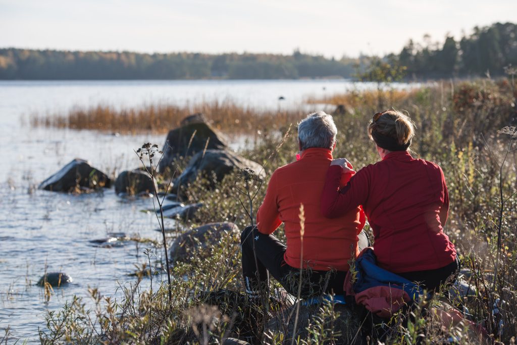 Två människor som sitter vid vattenkanten på en sten.