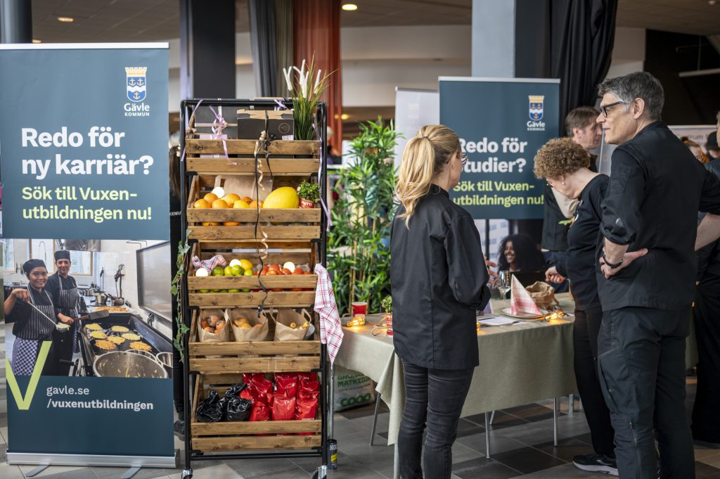 Personer som står vid ett bord på en mässa.