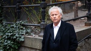 En man i rock framför en trapp