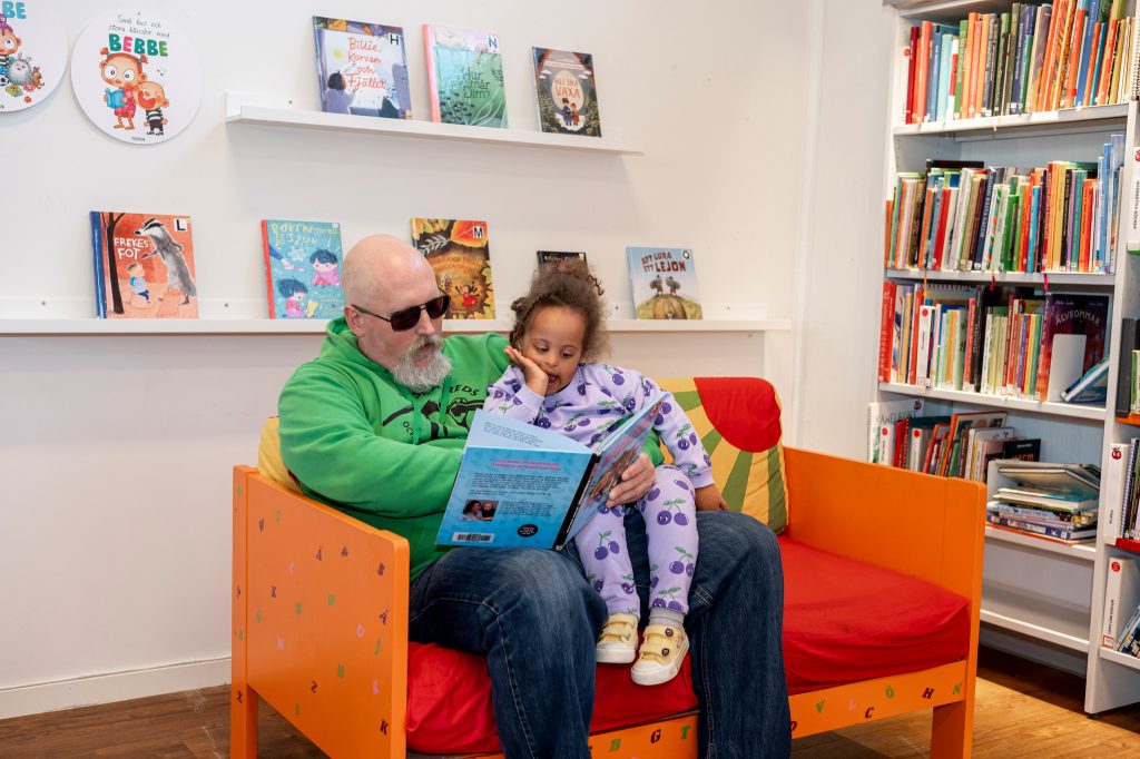 En vuxen och ett barn som läser tillsammans.