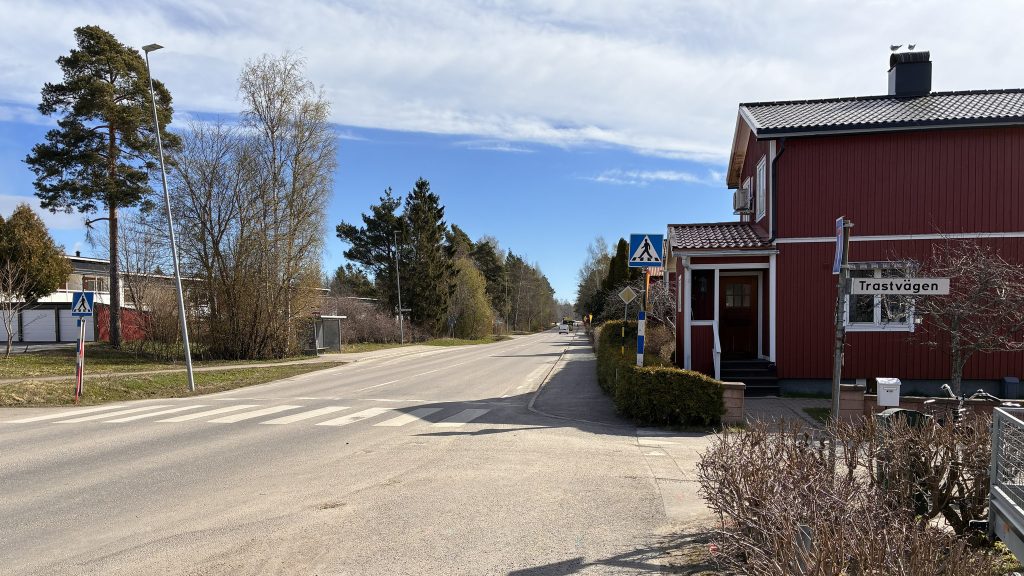 Vägkorsning vid Trastvägen. Rött hus och övergångsställe i bakgrunden.
