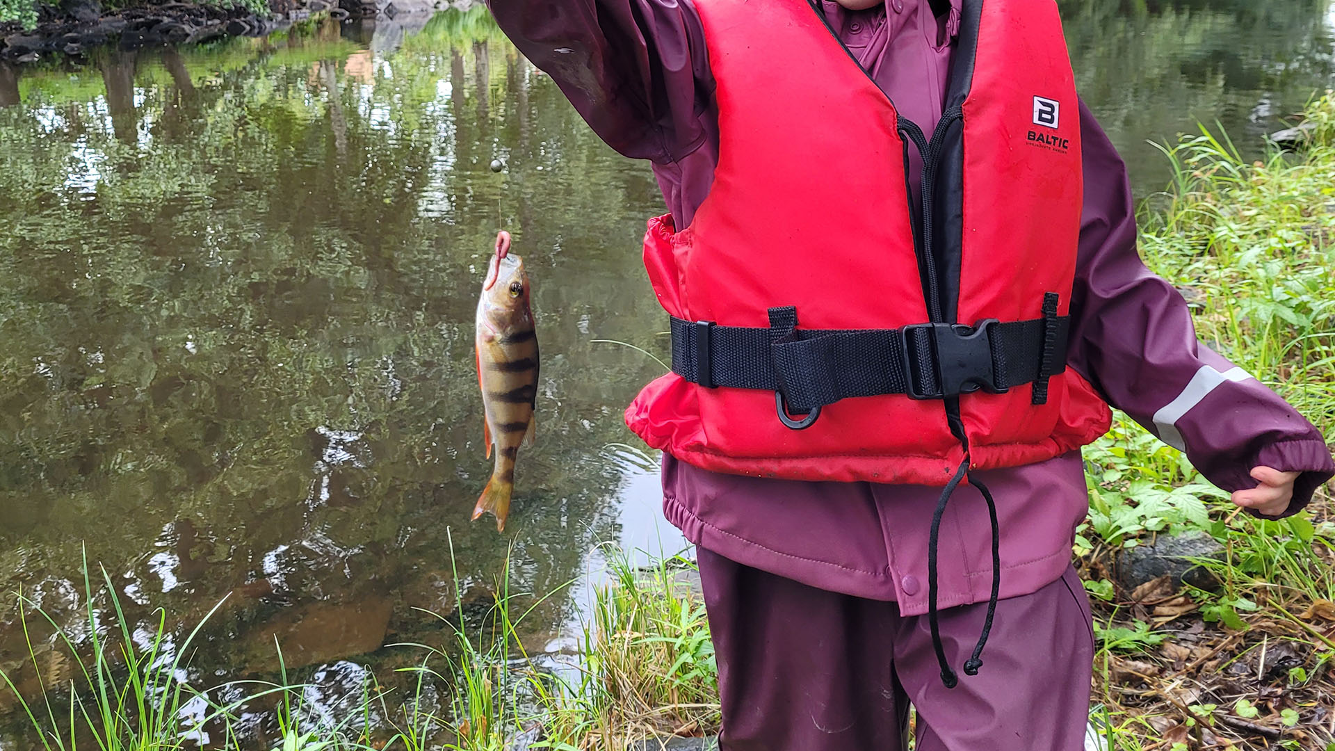 En flicka håller upp en fångad fisk