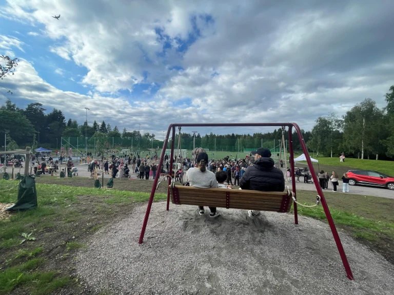 Två personer som sitter i en hammock vid en lekpark.
