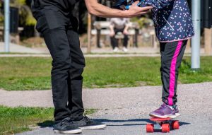 vuxen som hjälper barn hålla balansen på en skateboard