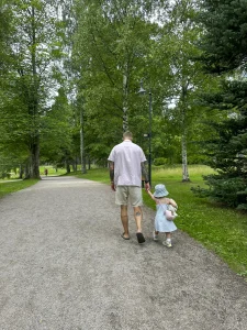 Barn och vuxen går i park och håller varandra i hand.