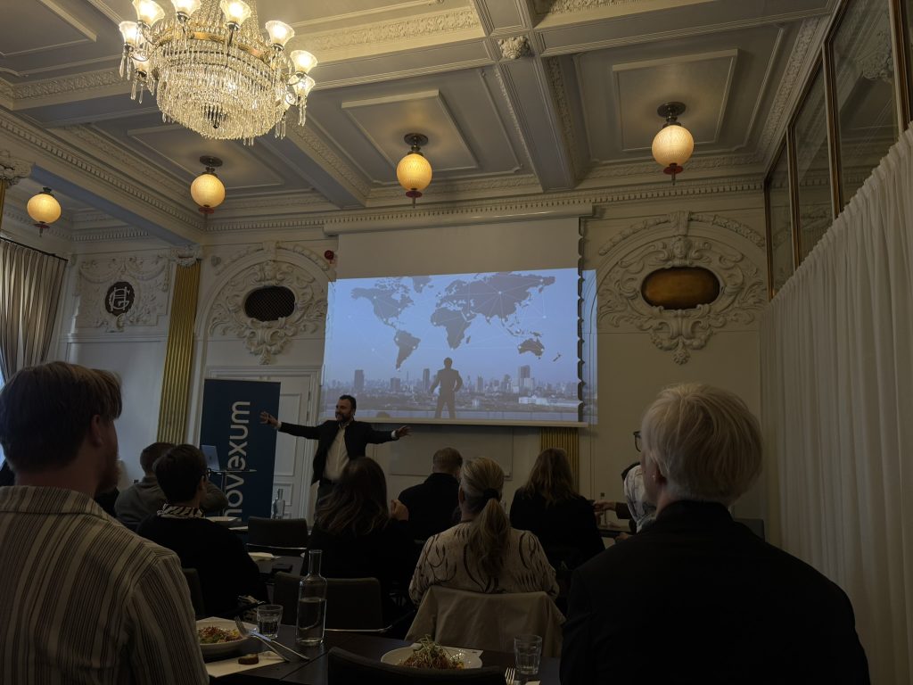 Stoyan Yankov står framför en grupp sittandes människor. Bakom honom syns en stor presentationsskärm.