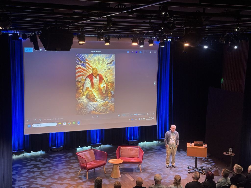 Bert Sundström står på en scen med en stor skärm i bakgrunden.