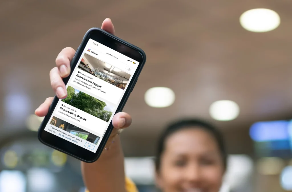 En kvinna som håller i en mobil där Smarta Kartan visas på skärmen