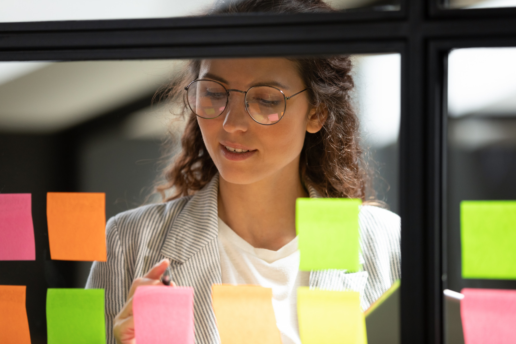 Person som står bakom en glasruta med massa postit-lappar.